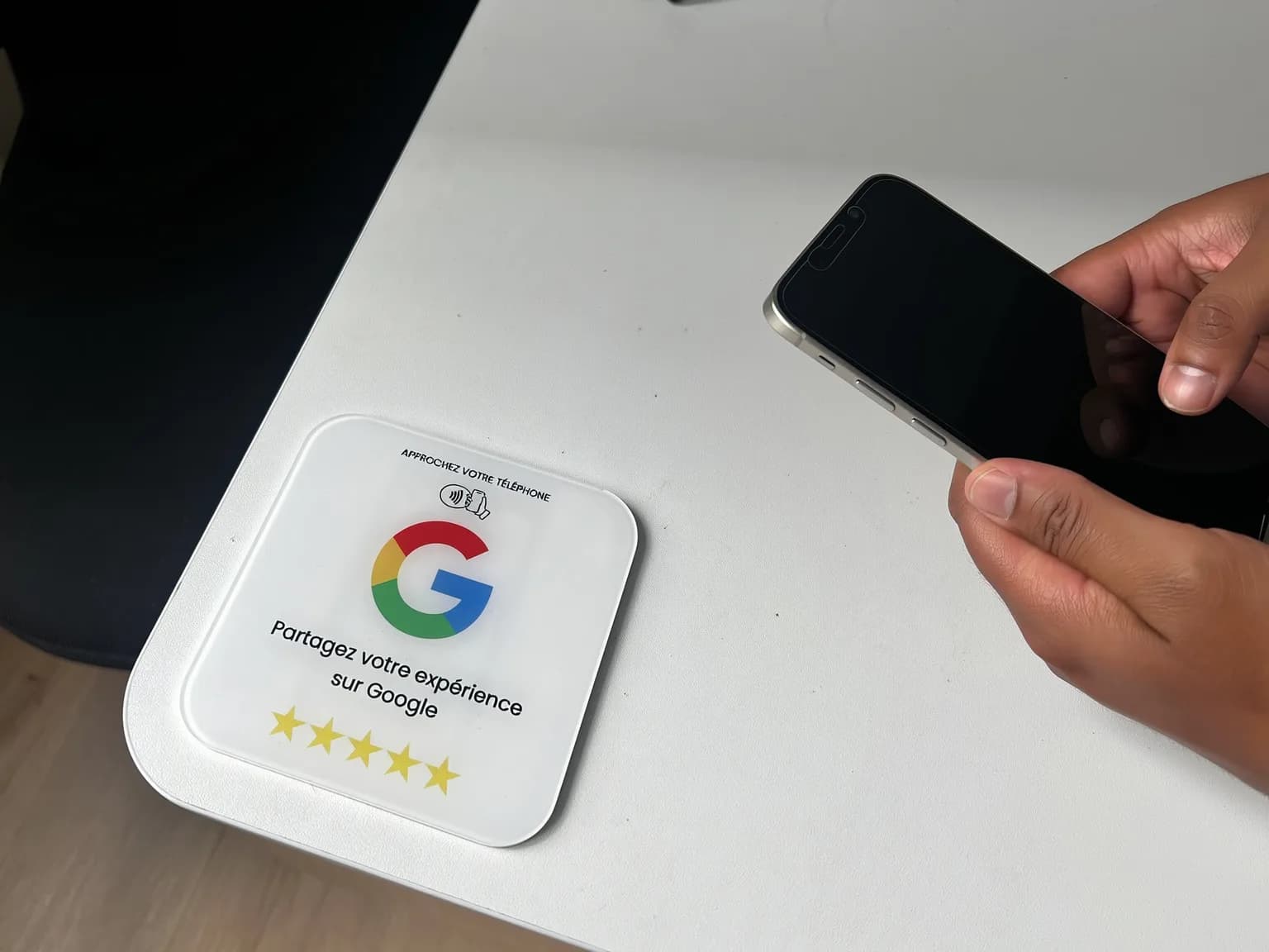 Client approchant son smartphone de la plaque avis Google posée sur le comptoir